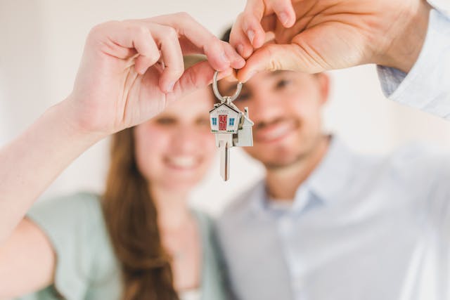 Happy couple holding a house-shaped keychain symbolizing their new home and financial success.