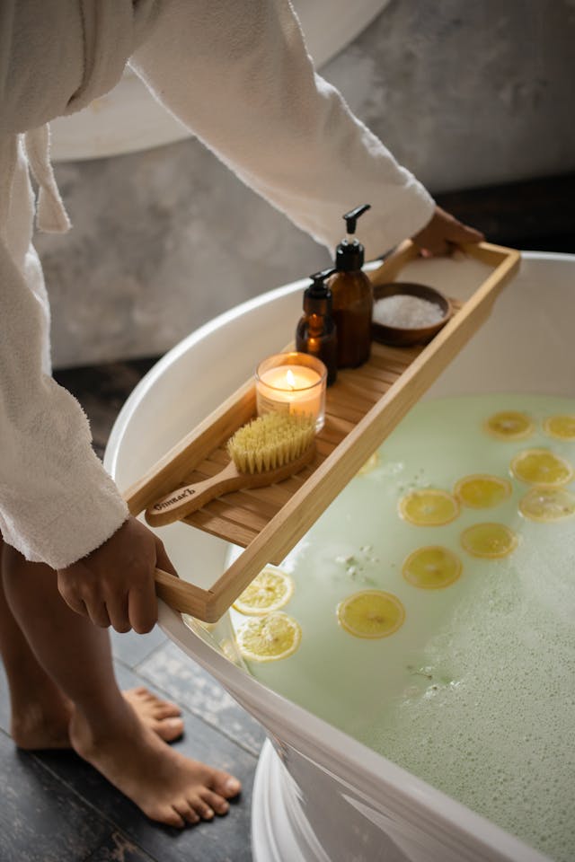 Monthly Splurge Ritual: A Spa Moment to Signal Abundance Person in bathrobe placing spa items over a luxury lemon bath as part of a monthly self-care ritual to embody financial abundance.