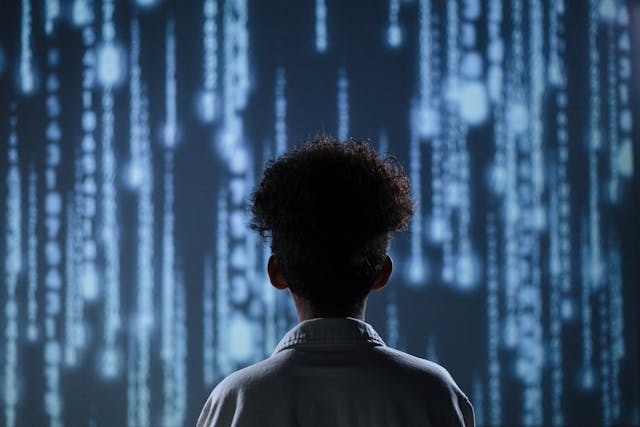 Wake Up from the Matrix: Person Facing Cascading Digital Code Back view of a person looking at a wall of cascading blue code, a visual metaphor to wake up from the matrix and see beyond the simulation.