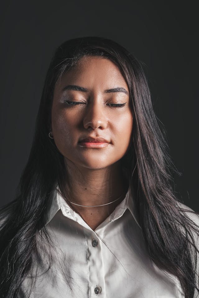 Calm Focus Before Rehearsal Woman with eyes closed practicing dr joe dispenza manifestation meditation, calm face against dark background.