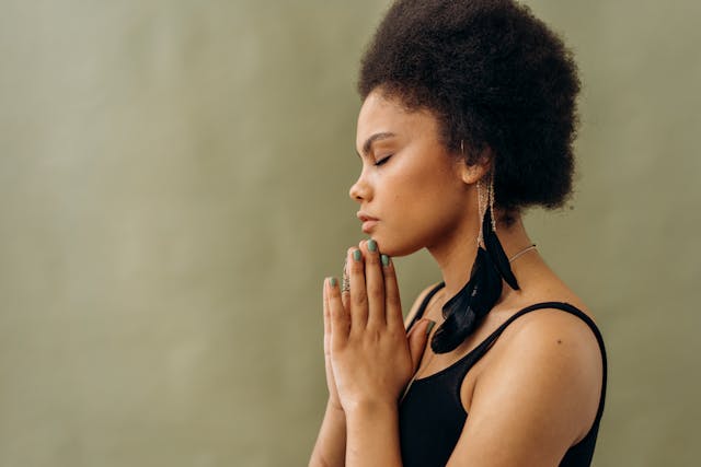Peaceful Prayer and Inner Reflection Woman meditating with hands in prayer pose and eyes closed, symbolizing spiritual connection and inner calm.