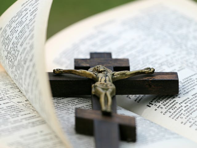 Wooden crucifix resting on the pages of an open Bible, representing devotion and guidance