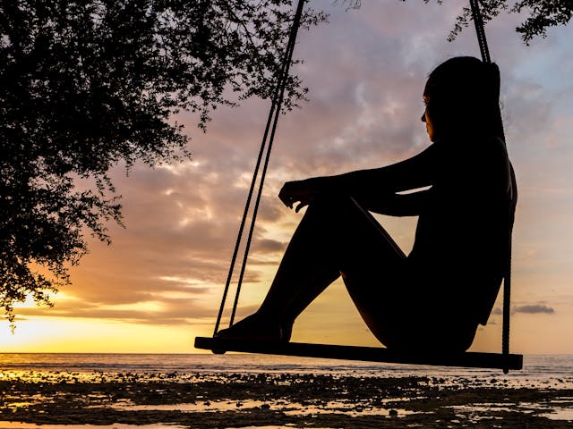 Sunset Reflection: Listening to Your Heart Silhouette of a person on a swing at the beach during a peaceful sunset