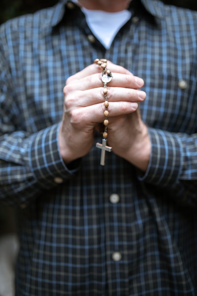Praying with a Rosary: Listening for God’s Plan Close-up of clasped hands holding a wooden rosary while praying about what is God’s plan for your life