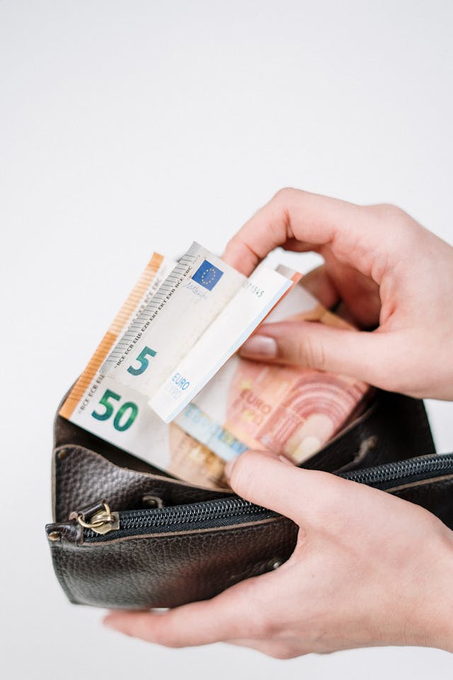 Daily Choices: How Can You Increase Your Income Hand holding a wallet filled with euro notes, showing how can you increase your income by managing everyday money decisions