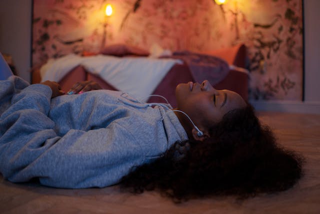 Woman relaxing on the floor with headphones in a calm bedroom to reset before crafting affirmations