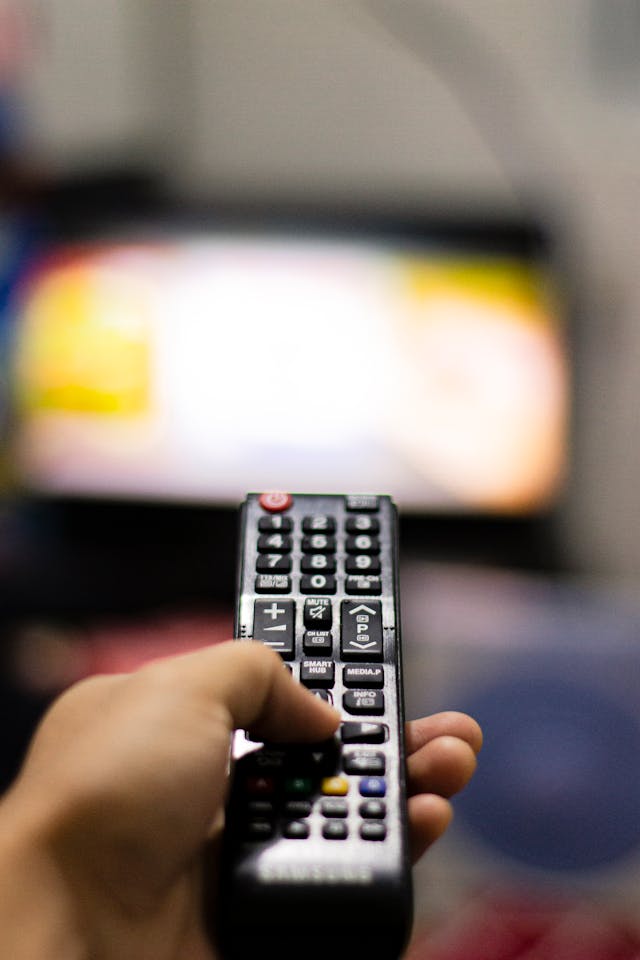 Hand holding a TV remote as a metaphor for directing focus in neuroplasticity and manifestation
