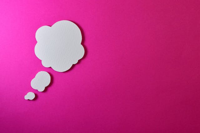White thought bubble on a bright pink background symbolizing how thoughts create reality