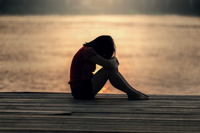 Emotional Shifts: How to Raise Your Vibration to Manifest Peace Person sitting alone by the water reflecting on how to raise your vibration to manifest inner peace