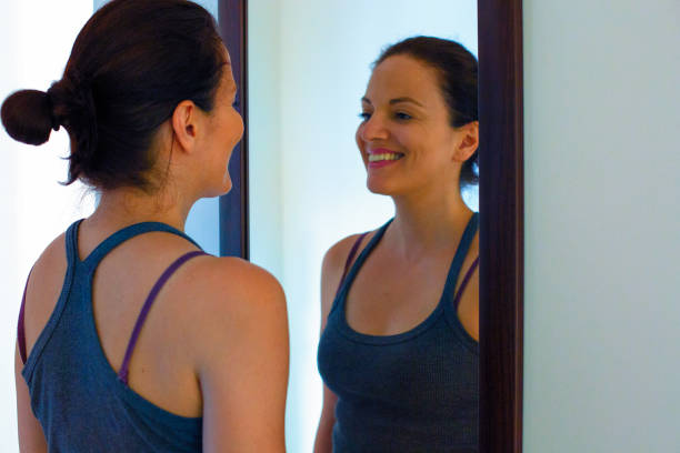 Mirror Practice — Daily Manifestation Routine for Self-Belief A smiling woman looks at herself in the mirror, practicing positive affirmations as part of her daily manifestation routine.