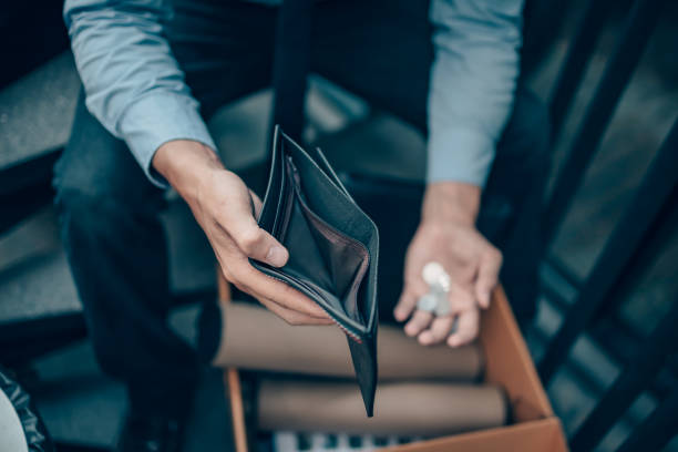 Close-up of a man holding an empty wallet with a few coins after job loss.