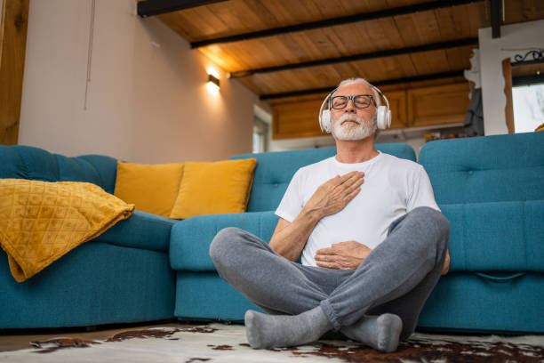Guided Breathwork for CE5 Meditations Older man sits cross-legged with headphones, one hand on chest and one on belly, practicing guided breathwork for ce5 meditations.