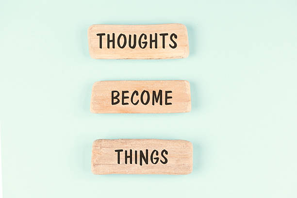 Wooden blocks arranged vertically with the phrase “Thoughts Become Things” on a light pastel background.