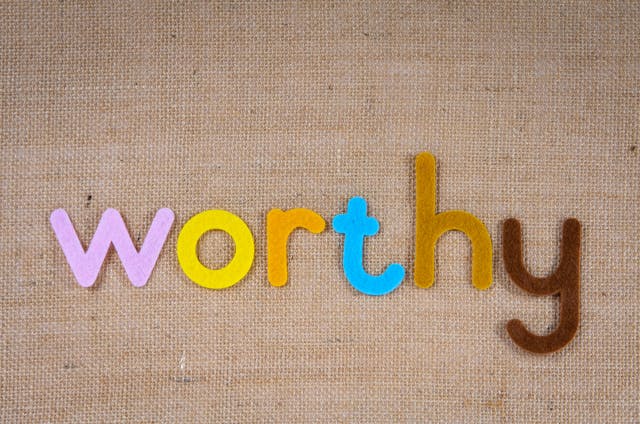 Colorful felt letters spelling “worthy” on a burlap background, symbolizing confidence and empowerment through daily affirmations for self worth.
