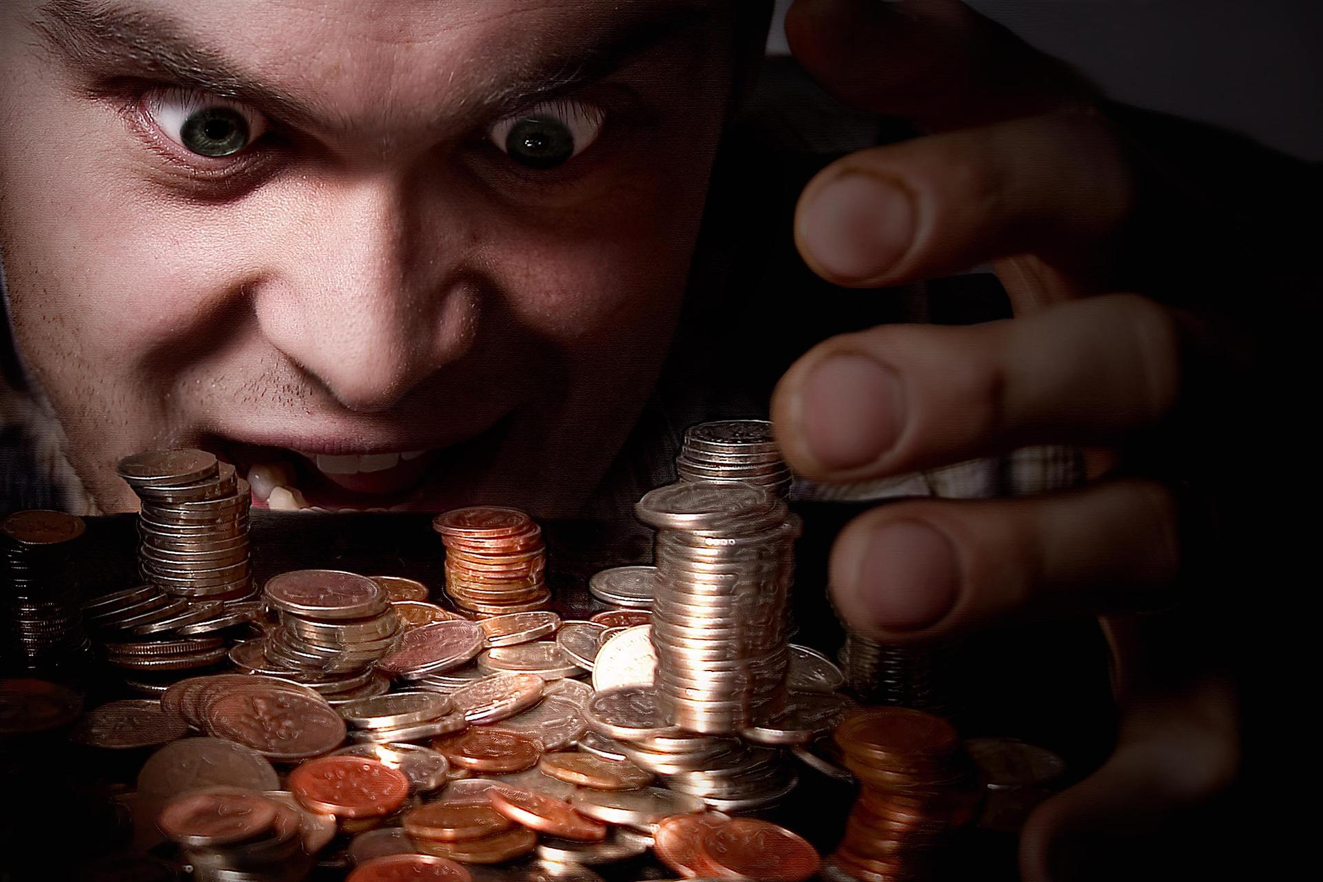 Scarcity vs Abundance Mindset Close-up of a man intensely staring at stacks of coins and loose change on a table, symbolizing scarcity mindset and financial obsession.