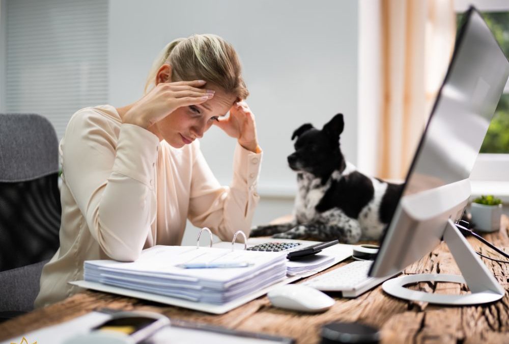 Money Manifestation Signs and Detaching from Your Bank Balance A stressed woman sitting at a desk looking worried while reviewing financial documents and a computer, representing emotional reactions to money and money manifestation signs.